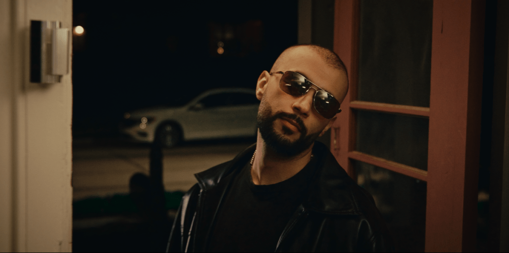 Finesse - 2025 movie still young man with glasses at the door